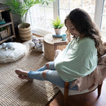 Ingenuity Good to Go 4-in-1 Multi-Use Cover in Fern pattern draped over baby carrier showing nursing cover and scarf use