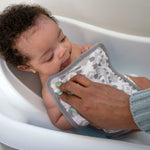 Baby being bathed with a gray and white patterned washcloth