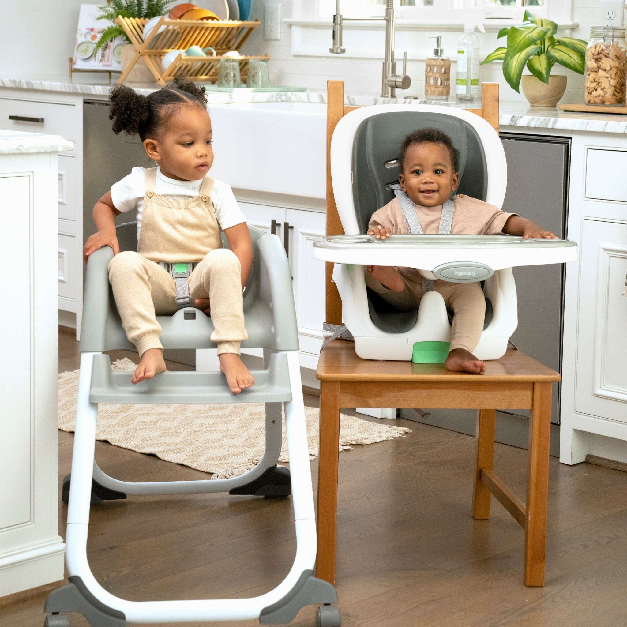 Two children sitting in adjustable high chairs in a kitchen.