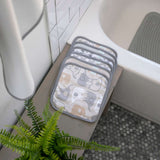 Set of bath mats with elephant pattern on a bathtub ledge next to a plant.