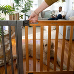 Ingenuity The Thruway 60W Series baby and pet safety gate with honey oak wood door and metal frame installed in doorway