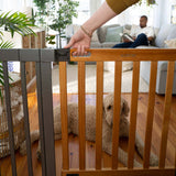Ingenuity The Thruway 60W Series baby and pet safety gate with honey oak wood door and metal frame installed in doorway