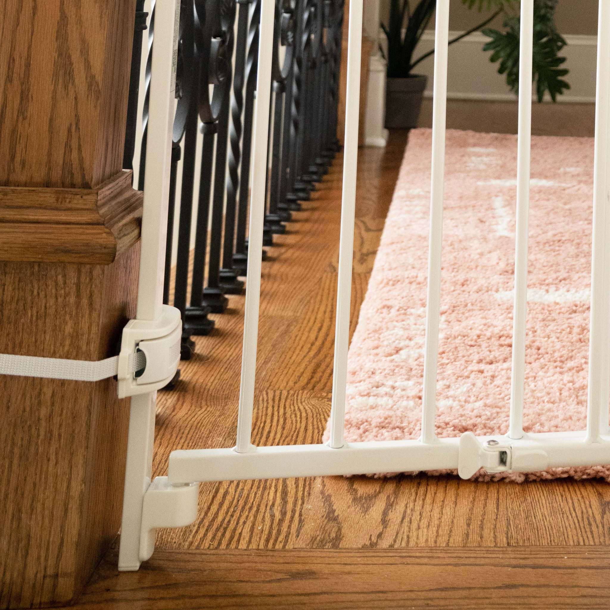 White metal safety gate installed at stairway; part of the Ingenuity The Stairway+ 46W Series for child and pet security.